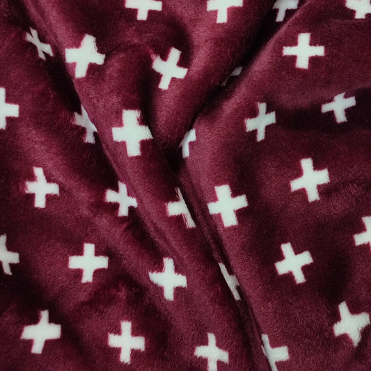 Tela Coralina con estampado de cruces con fondo granate
