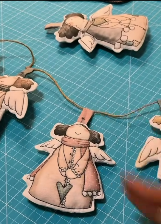 Hadas navideñas de tela acolchadas y unidas con cordón para formar una guirnalda
